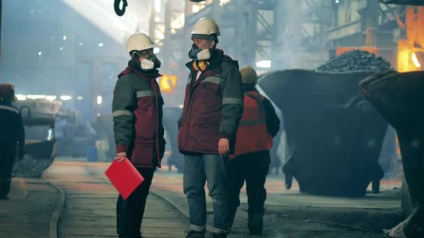 Współpracownicy zakładów metalurgicznych rozmawiają w miejscu pracy. Wnętrze hutnictwa. — Wideo stockowe