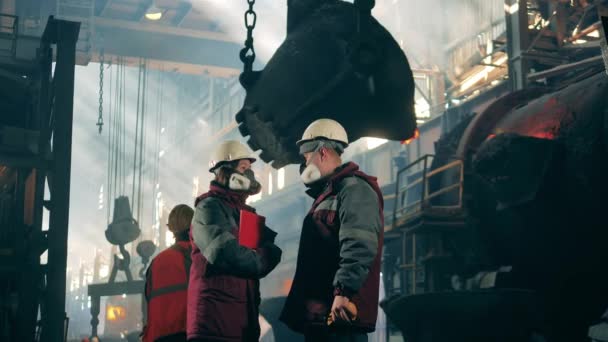 Steel workers in protection wear are talking in the factory — Stock Video