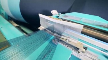 İnce iplikler büyük bir makaranın üzerinde dönüyor.