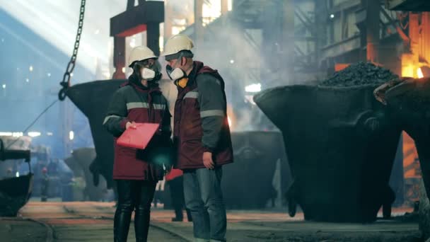 Co-workers in safety wear are talking in the metallurgical plant unit — Stock Video