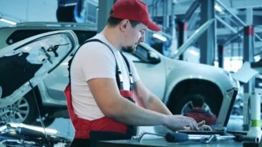 Erkek oto tamircisi bir otomobil tamirhanesinde çalışıyor.