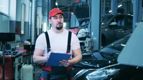 자동차 수리 점에서 필기를 하고 있는 남자 자동차 수리공 — 비디오