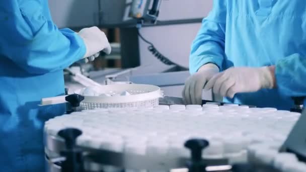 Arbeiter der Anlage verschließen Plastikwannen auf dem Förderband. Produktionslinie für pharmazeutische Fabriken. — Stockvideo