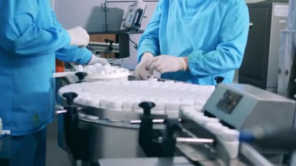 Línea de producción de fábrica farmacéutica. Los empleados de la fábrica están cerrando pequeñas tinas de plástico — Vídeo de stock