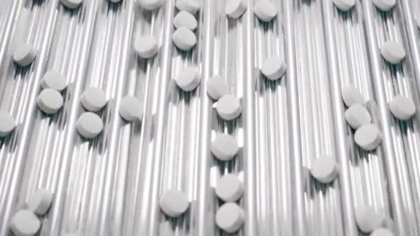 Металлический конвейер с рядами белых таблеток, движущихся вдоль — стоковое видео