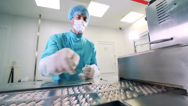 Hombre especialista está reemplazando las píldoras de la cápsula en el transportador. Línea de producción de fábrica farmacéutica. — Vídeo de stock