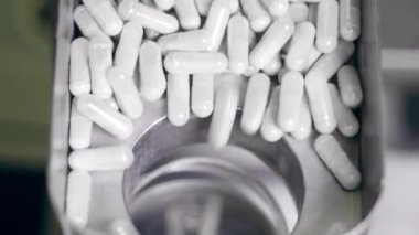 Kapsül hapları taşıyıcıdaki bir deliğe düşüyor.