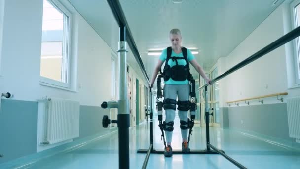 La patiente porte un exosquelette pendant la pratique de la marche — Video