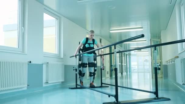 Jeune femme s'entraîne à marcher tout en portant l'exosquelette — Video