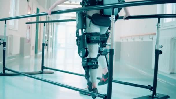 Kvinnlig patient övar på att gå i exoskelett på sjukhus — Stockvideo