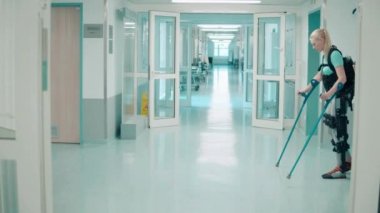 Bir kadın hastanenin dış iskeletinde yardım alarak yürüyor.