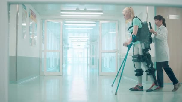 Le docteur aide une femme à marcher le long de l'hôpital en exosquelette — Video