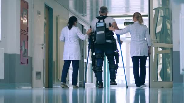 Врачи помогают человеку ходить в экзоскелете — стоковое видео