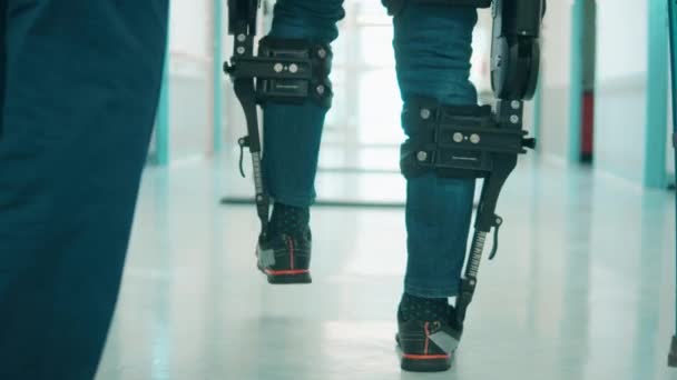 A person is training to walk in the exoskeleton with assistance — Stock Video
