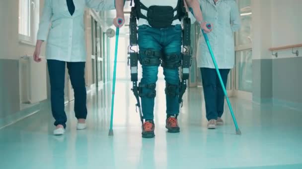 Salle d'hôpital avec un homme marchant dans l'exosquelette avec l'aide — Video