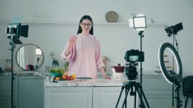 Genç kadın stüdyoda yemek pişirirken filme alınıyor. Çevrimiçi vlog kavramı, kadın blogger kayıt videosu, çevrimiçi yayın kavramı.