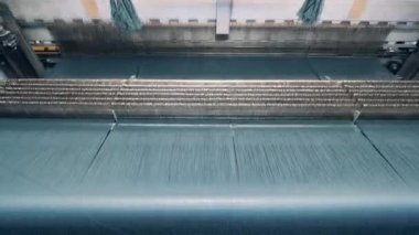 Bir sürü ipliği olan dokuma makinesi hızla geçiyor.