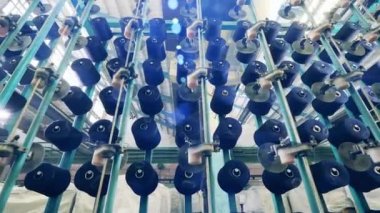 Duvarda mavi iplikli birden fazla makaralar dönüyor.