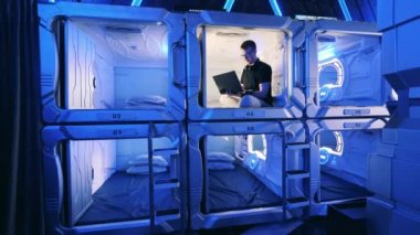 Odalardan birinde laptop kullanan bir adamla kapsül oteli.