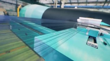 Bir örgü makinesinin büyük makarası üzerinde ipliklerle dönüyor.