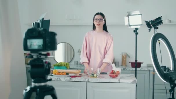 En kvinna lagar mat i videostudion medan hon filmar. Online vlog koncept, kvinnlig bloggare inspelning video, online streaming koncept. — Stockvideo