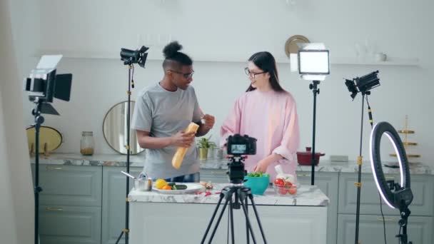 Online vlog, bloggers recording video, online streaming concept. A couple of young people are cooking while filming in the studio — Stock Video