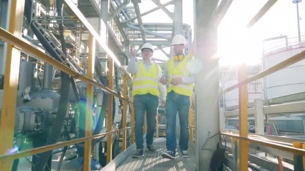 Dois engenheiros estão caminhando ao longo da fábrica de refinaria de petróleo — Vídeo de Stock