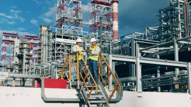 Εγκαταστάσεις διυλιστηρίων πετρελαίου με δύο μηχανικούς να συζητούν — Αρχείο Βίντεο