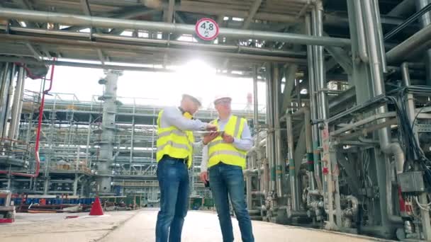 Ingenieurs bespreken plannen in de olieraffinaderij. — Stockvideo