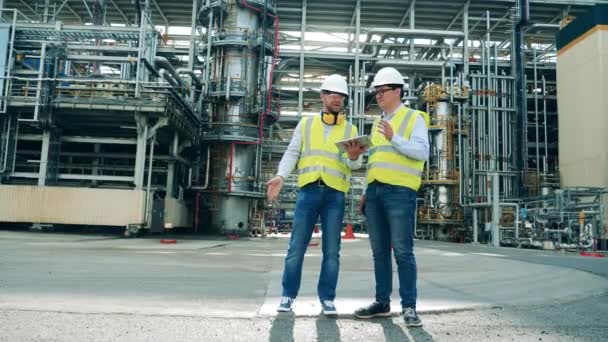 Ingenieros de refinería de petróleo están discutiendo planes en las instalaciones — Vídeo de stock