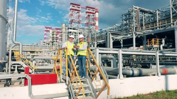Instalaciones de refinería de petróleo con ingenieros hablando entre sí — Vídeo de stock