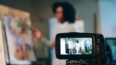 Kamera Afrikalı Amerikalı bir kadının sanat dersini çekiyor.