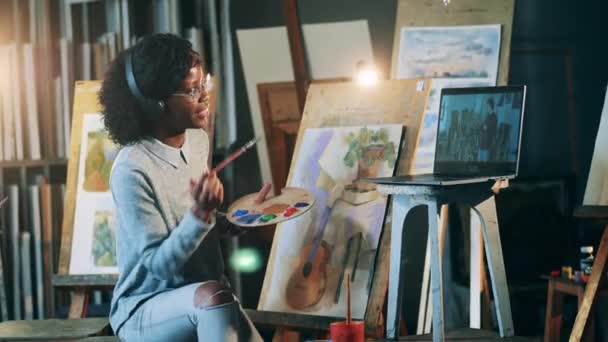 La femme afro-américaine a un cours de peinture à distance. Concept d'éducation artistique. — Video