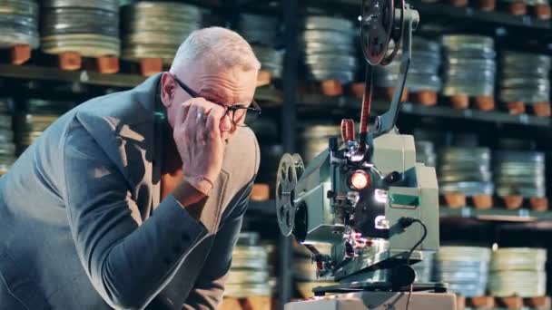 Ρετρό, κλασσική τεχνολογία. Αρχειοθέτης ρυθμίζει ένα vintage προβολέα ταινιών κατά την προβολή — Αρχείο Βίντεο