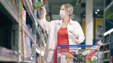 Alışveriş yaparken bir kadın yüz maskesi takıyor. Kadın süpermarkette, tüketim konsepti.