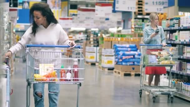 Supermarkt-Gang mit Frauen, die Dinge aussuchen, um sie zu kaufen. Käufer, Kunde im Lebensmittel-, Lebensmittel- und Supermarkt. — Stockvideo