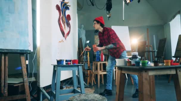 Studio sztuki z wytatuowanym malarzem kończącym obraz płótna — Wideo stockowe