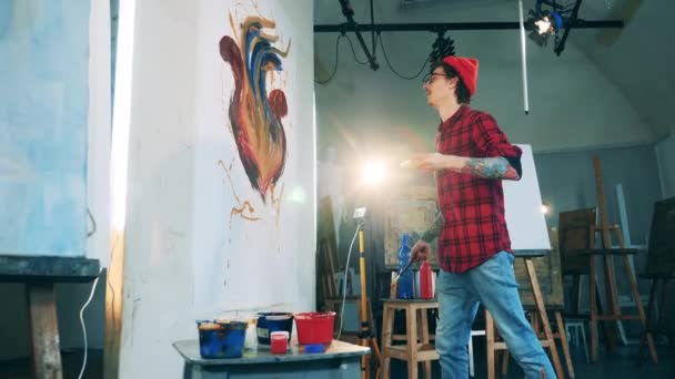 Tetovaný muž maluje květinu na plátno ve svém ateliéru — Stock video