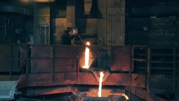 Fonderie avec un ouvrier d'usine contrôlant la fusion — Video