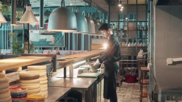 Un hombre está cocinando detrás del mostrador en el restaurante — Vídeo de stock