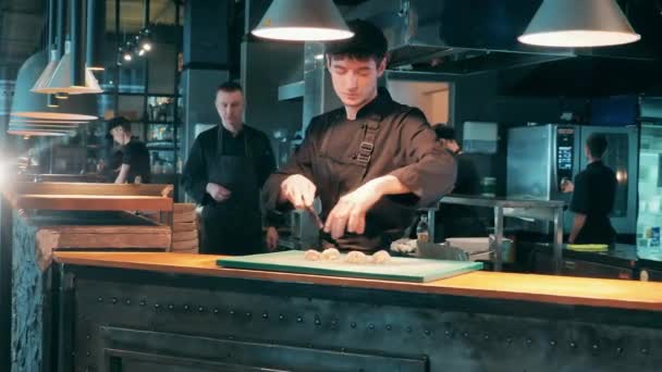 Ресторанний кухар подрібнює овочі на обробній дошці — стокове відео