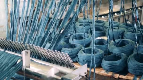 Gekleurd garen wordt afgewikkeld door een fabrieksmechanisme. Productieapparatuur van textielfabrieken. — Stockvideo