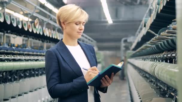 Vrouwelijke expert maakt aantekeningen in de textielfabriek — Stockvideo