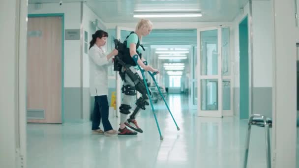 Doktor pomáhá pacientce chodit v exoobleku. — Stock video