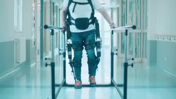 Male patient in the exosuit is walking along the hospital by himself — Stock Video