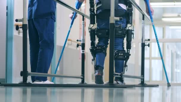 A person is learning to walk in the exoskeleton with medical help — Stock Video