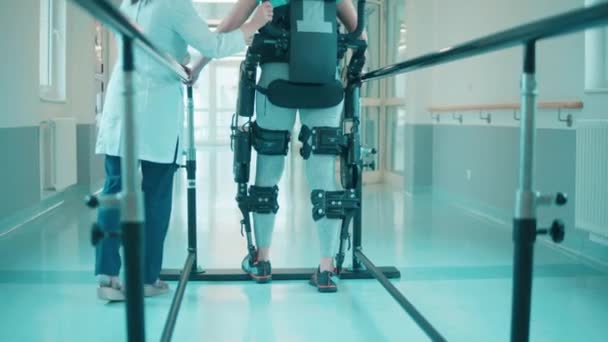 Doktor pomáhá postiženému muži v exoskeletonu. — Stock video