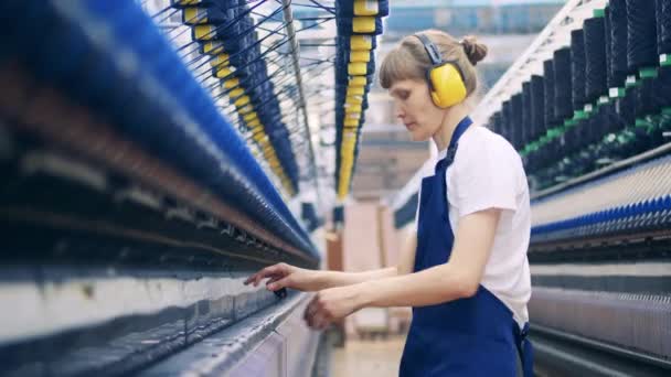 Vrouwelijke werkneemster haalt extra draden uit de machine. Productieapparatuur van textielfabrieken. — Stockvideo