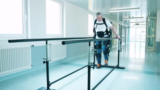 En man med funktionshinder försöker gå klädd i exoskelett — Stockvideo