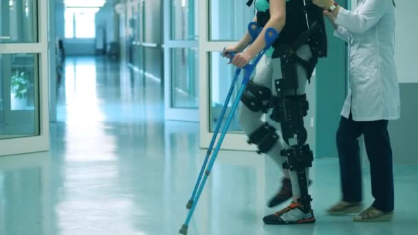Lääkäri auttaa potilasta kävelemään, kun käytät exosuitia — kuvapankkivideo